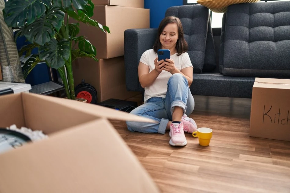 Girl with down syndrome sitting on floor of home looking at phone