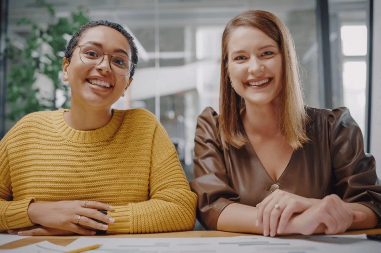 Two woman sitting at table and smiling at camera
