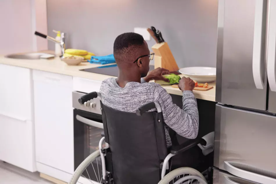 Person in wheelchair chopping vegetables in kitchen